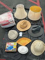 Lot overview showing mattress pad, lampshades, hats, fan, light fixture, Flash Card