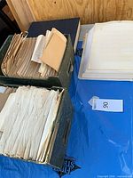 Two green storage boxes filled with loose archival pages, additional stack of dissertation pages adjacent