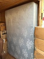 Front view of full mattress standing upright in shed