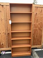 Full view of tall light cherry laminate bookcase with seven shelves