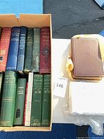 Box containing multiple cloth-bound hardcovers with additional wrapped volumes beside it