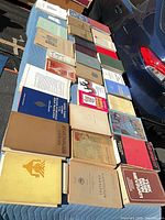 Overview of approximately thirty academic books laid out on table showing varied bindings and subjects