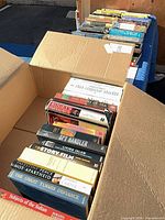 Open box showing rows of books with visible spines including Subjects of the Sultan, The Great Turk's Defiance, Palestine: Peace Not Apartheid, Spy Handler, The Story of Film, The Story of Tea