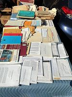 Overall view of assorted notebooks, booklets, loose papers and folders spread on table