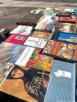 Top-down view showing entire assortment of mixed hardcover and paperback books on table