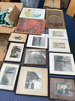 Group shot of approximately 13 framed artworks laid out on floor