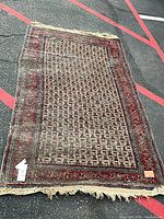 Full view of worn Persian-style rug runner showing overall pattern, size reference tag visible.