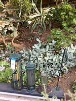 Three bird feeders and stand in garden setting