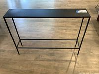 Front view of slim black metal console table