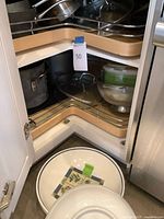 Corner cabinet showing assorted cookware and ceramic bowls
