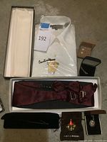 All items overview: boxed tuxedo shirt, burgundy cummerbund, cufflinks, carousel brooch, painted pendant, script pin