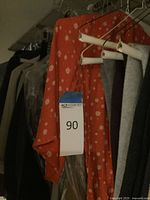 Hanging garments including orange polka-dot dress and assorted sweaters