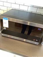 Front view of LG stainless steel microwave with mirrored door and digital clock