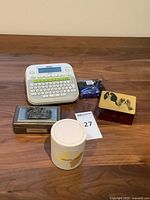 All items grouped on table: label maker, extra cassette, candle, two decorative boxes