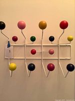 Front view of white wire coat rack with multicolor ball knobs