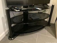 Front view of black glass TV stand with three shelves
