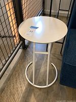 Full view of white painted metal side table beside railing