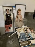 Overview of four dolls in boxes with clothing