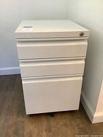 Front view of white 3-drawer metal file cabinet on casters