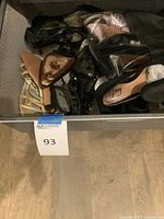 Multiple pairs of women’s shoes in mesh drawer including gold sandals and black patent heels
