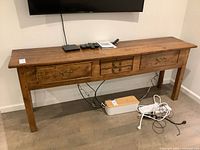 Front view of wooden console table beneath wall-mounted TV