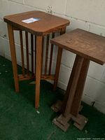 Two wooden pedestal stands against wall