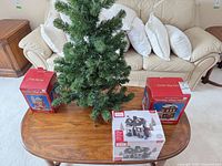 Tree and three boxed porcelain houses on table