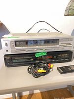 Technics receiver stacked over Magnavox CD player with cables and remote
