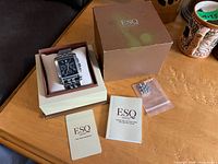 Watch in open inner box alongside outer sleeve, booklet, card and spare links