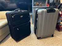 Two suitcases side by side, one black softside, one silver hardshell