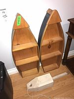 Two boat-shaped wood shelves and white block on floor