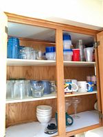 Cabinet with full lot showing mugs, glasses, bowls, storage containers