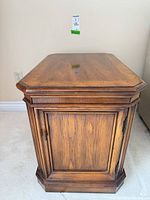 Front view of oak side table showing paneled door and pull