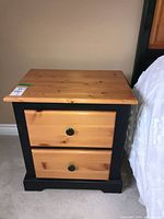 Front view of side table showing two pine-front drawers with black knobs and dark frame