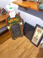 Wood chef menu sign, shadowbox, and framed poster leaning against wall