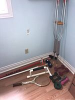 Group view of all items: curling brooms, crutches, tennis racket, dumbbells