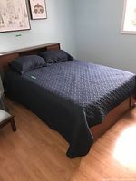 Bed frame in room with mattress and bedding in place