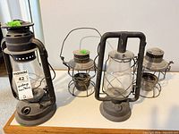 Group shot of four vintage lanterns displaying size differences and missing parts