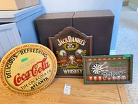 Three wood advertising signs leaning against ottoman