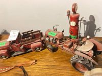 Overview of red tin truck, tractor and gas pump on wooden surface