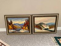 Both framed paintings side by side against wall