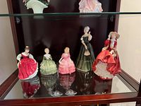 Front view of all five Royal Doulton figurines in display cabinet