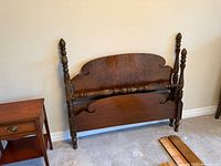 Front view of assembled headboard and footboard showing carved posts and shaped panels