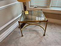 Perspective view of full table showing glass top, brass frame, legs and stretcher