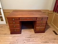 Front view of wood executive desk showing drawers and brass pulls