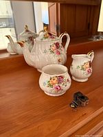 Teapot, creamer and sugar bowl displayed on wooden surface