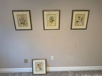 Three framed prints on wall, fourth on floor showing group