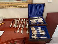 Open flatware chest showing utensils and loose pieces on dresser