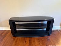 Front view of black TV stand showing frame and glass shelf