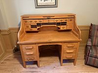 Front view of oak roll-top desk with tambour open showing interior cubbies and drawers